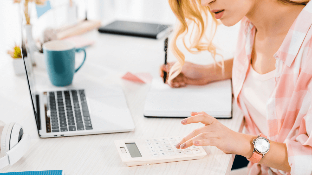 Woman using calculator and writing in notebook