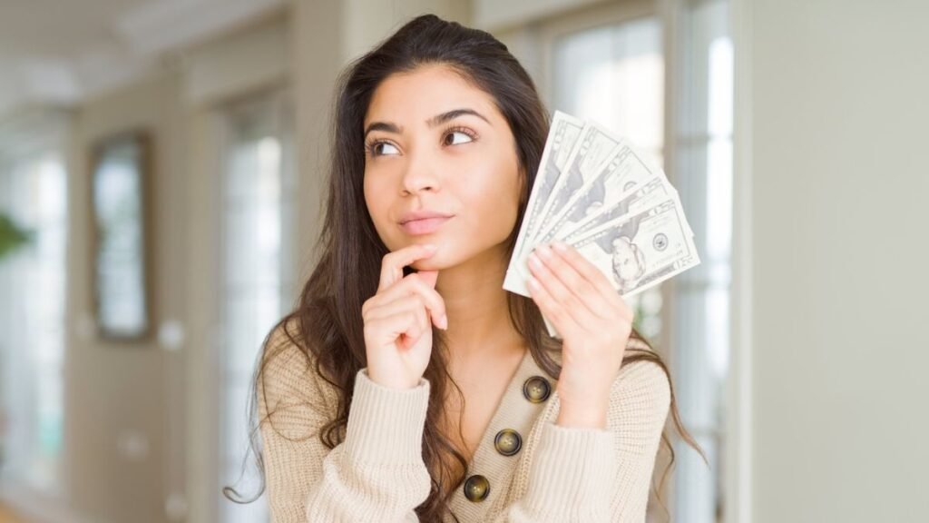 Young Woman Thinking While Holding Dollar Bills Cash Money MSN