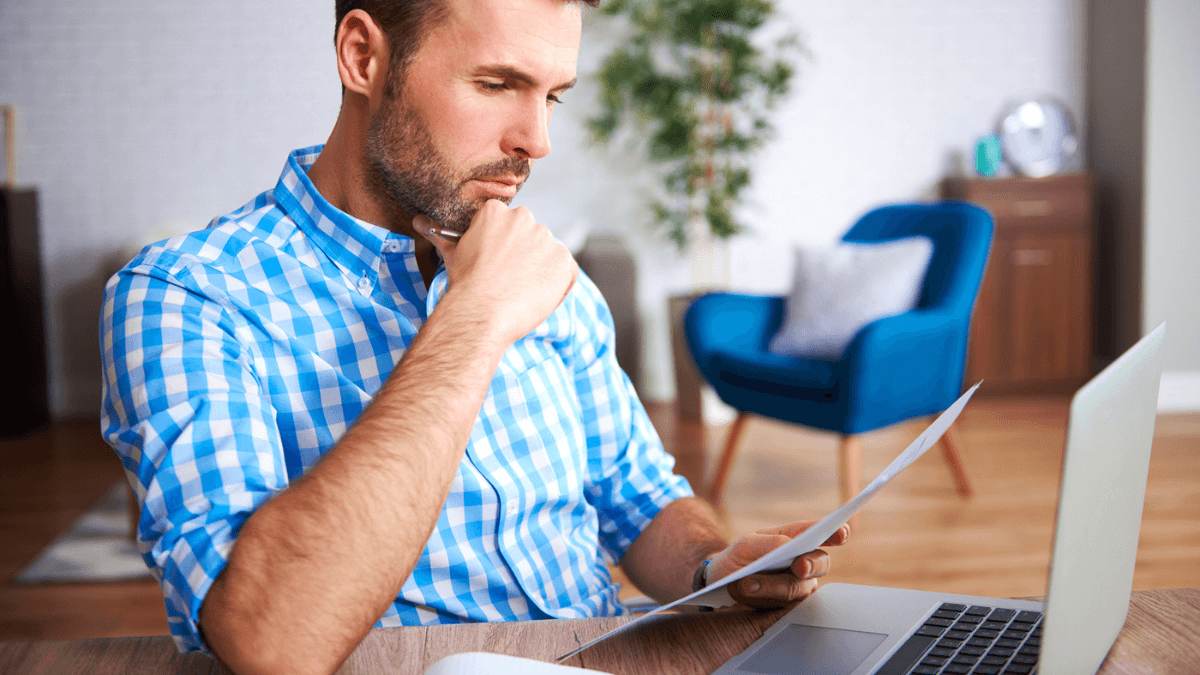 Businessman reading documents with laptop