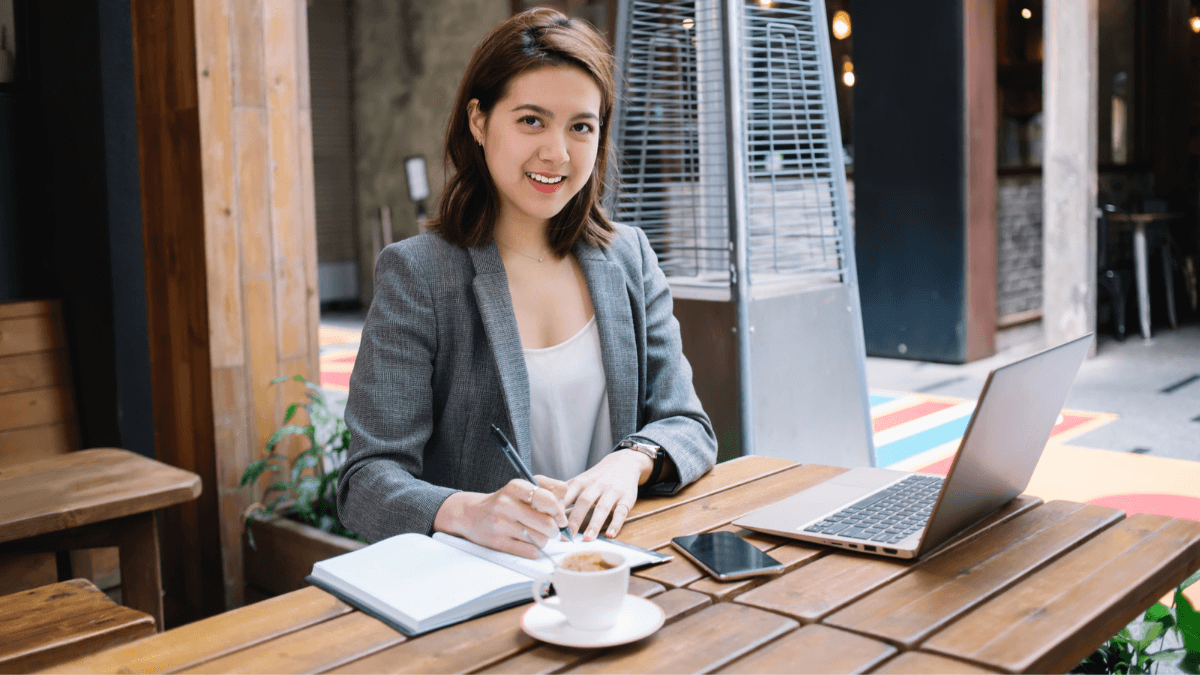 Smiling woman using laptop working in cafe