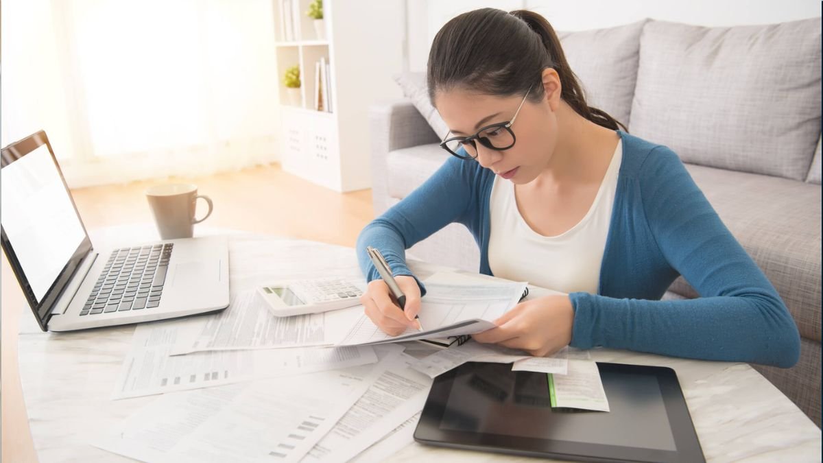 Woman using laptop and tablet to manage bills